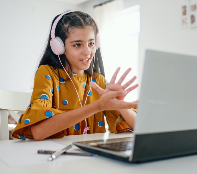 Chica en un escritorio que utiliza un ordenador portátil e inicia Norton Family