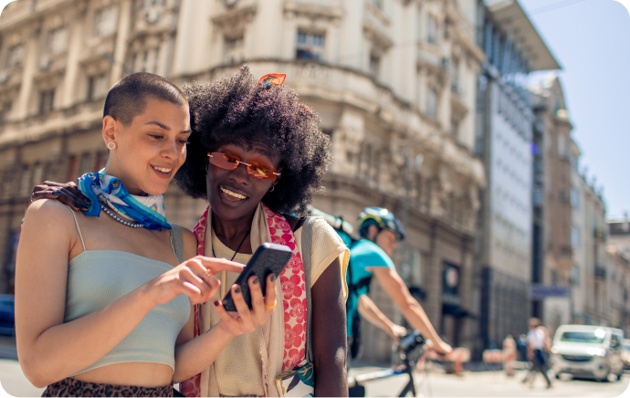 Dos mujeres sonrientes mirando juntas un teléfono