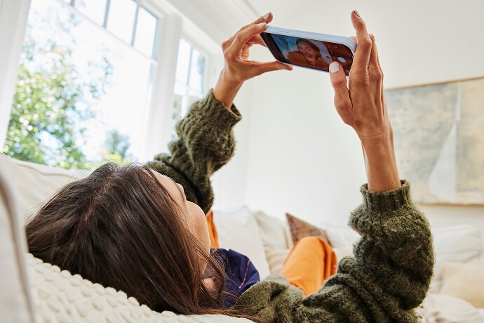 Mujer recostada mirando su teléfono móvil